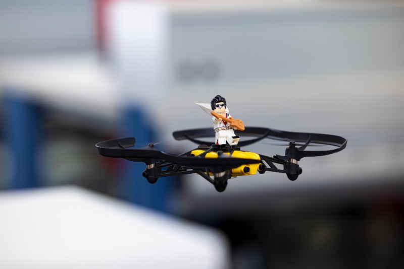 Eine Legofigur, die aussieht wie Elvis Presley, fliegt auf einer Drohne.