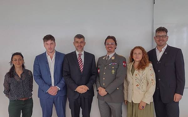 Personen stehen vor einer weißen Wand und posieren für ein Gruppenbild