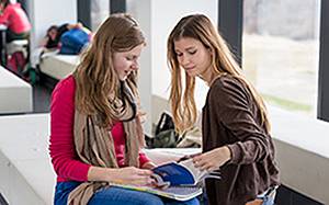 Zwei Studierende schauen gemeinsam in ein Buch