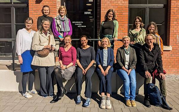 Zwölf Personen posieren im Sonnenschein für ein Foto