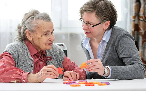 eine ältere und eine jüngere Frauen puzzlen gemeinsam