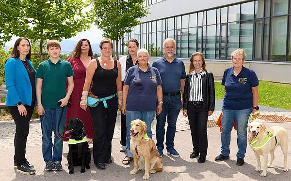9 Personen und 3 Hunde vor dem Gebäude der FH Campus Wien