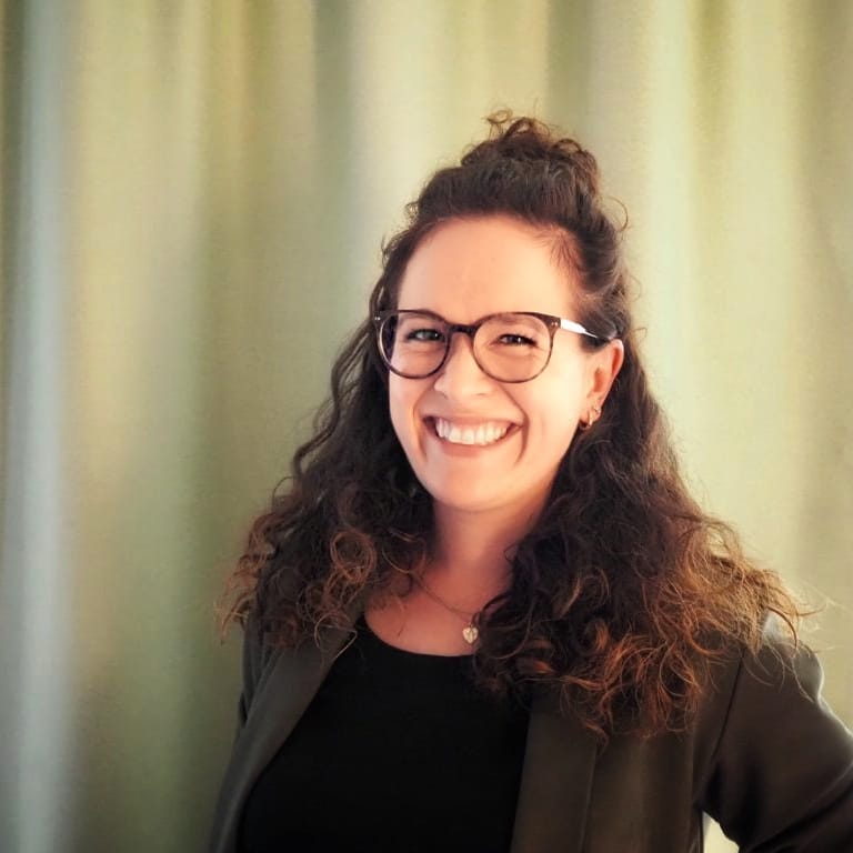 Smiling young lady with curly hair and glasses