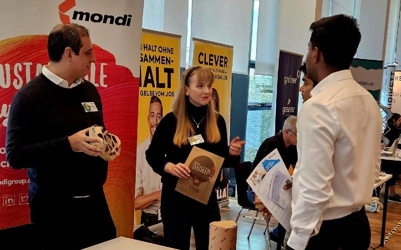 Drei Personen stehen bei einem Messe stand und unterhalten sich