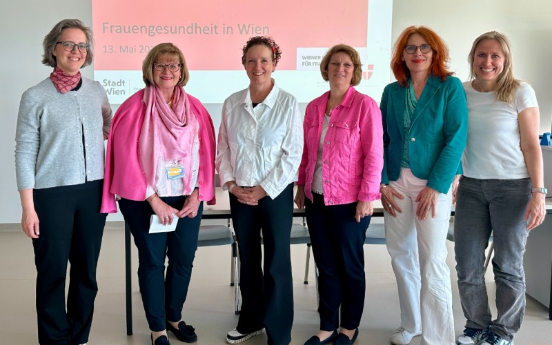Sechs Frauen stehen vor einer Leinwand und lächeln in die Kamera