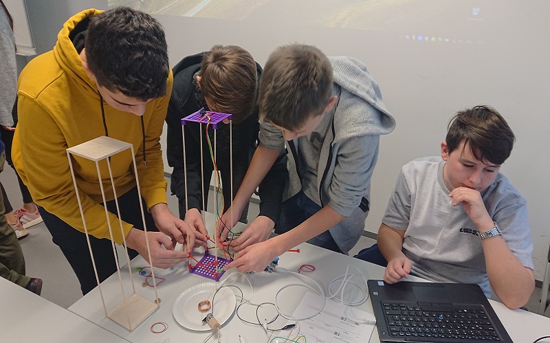 Vier Schüler beim Bauen eiens Turms und messen mit dem Laptop