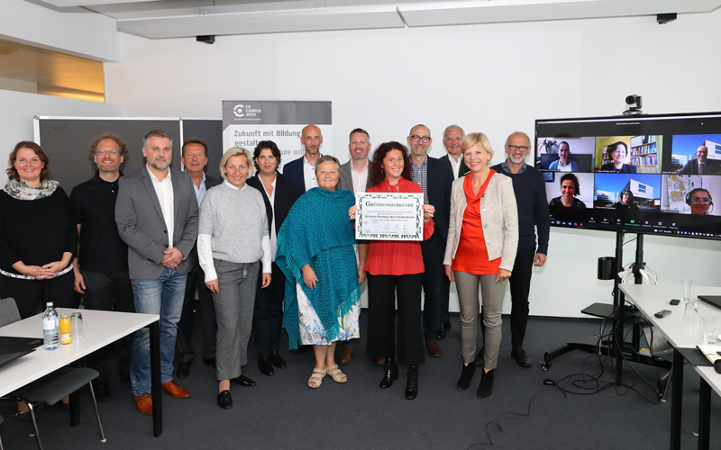 Gruppe von Menschen, eine Frau hält das Dokument "Charta für das Bündnis Nachhaltige Hochschulen" in die Kamera. Rechts sind Menschen via Zoom zur Sitzung zugeschaltet