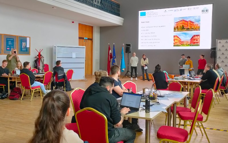 Stehende Menschen halten vor sitzendem Publikum eine Präsentation